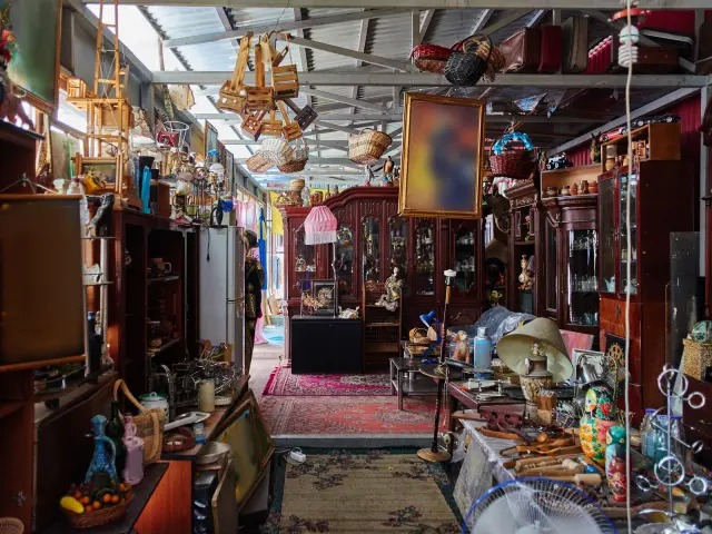 A crowded antique shop with furniture and hanging lamps